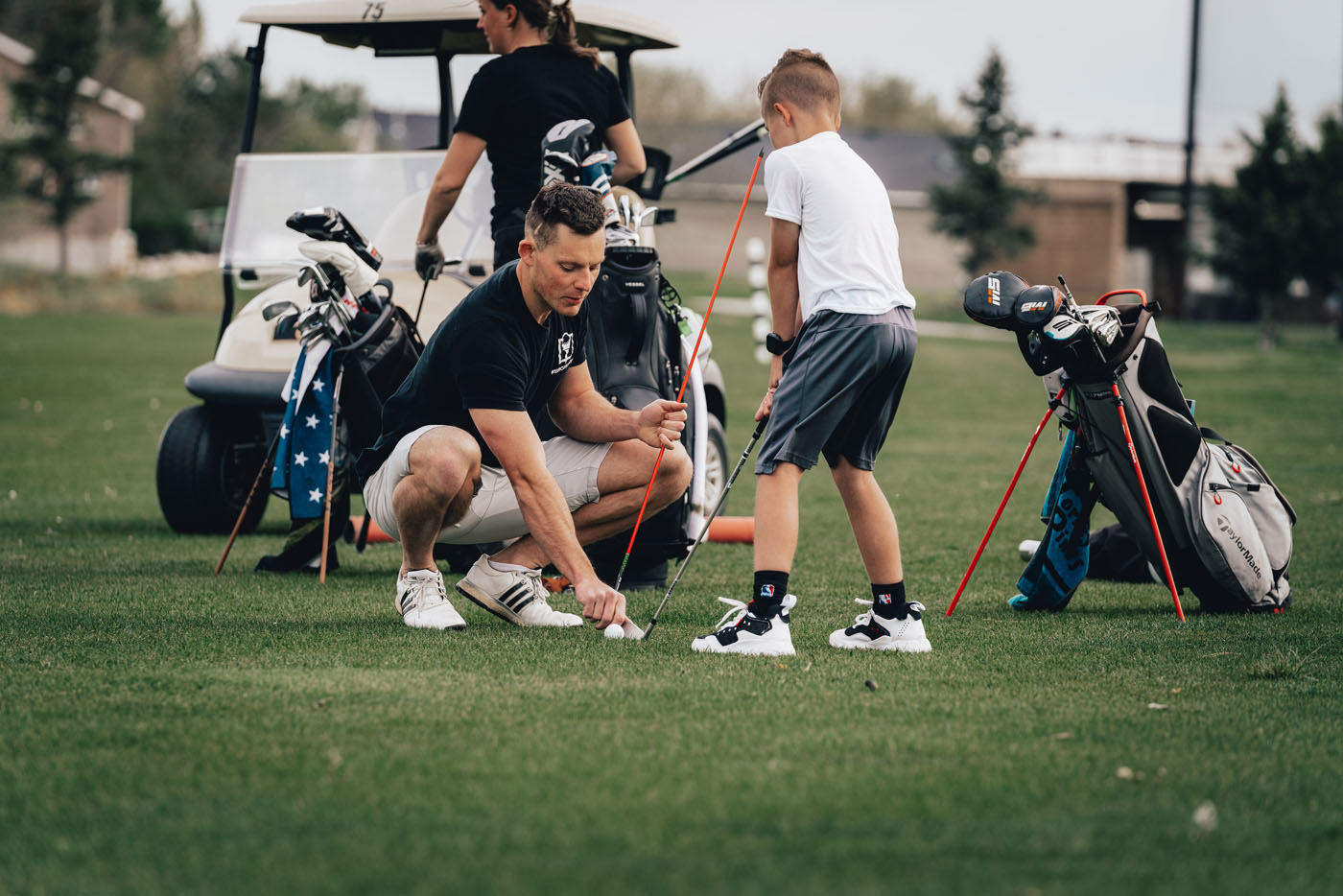 A Tee Box employee working with a group of kids on a golf course in The Woodlands, TX.